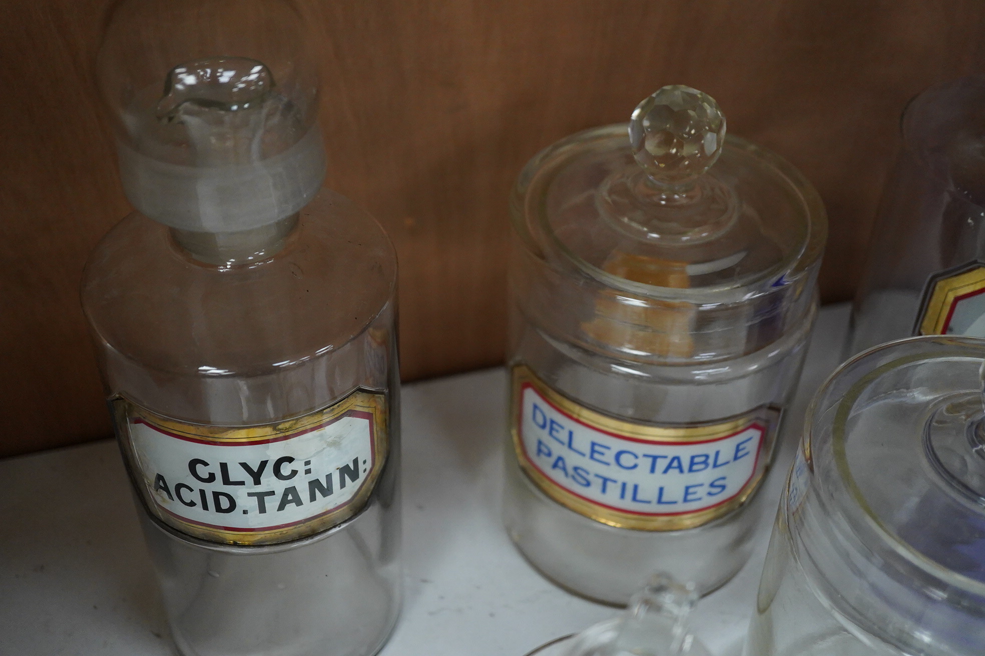Seventeen 19th/early 20th century glass apothecary jars with gilt rimmed labels; six blue glass, ten clear glass and a green glass example, labels including; Syr: Zingib:, Chloroform, Syr: Rhei:, Camphora, etc. tallest 2